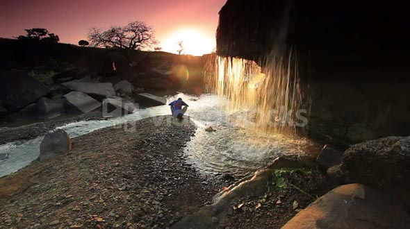 Child Watching a Waterfall and Tossing a Rock