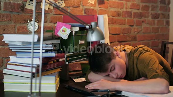 Tired student sleeping on desk after studying at home