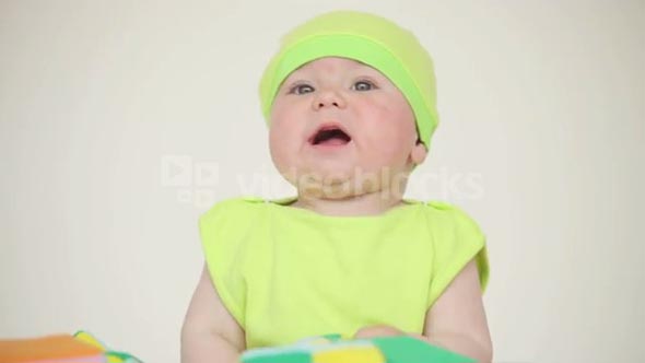 Baby with a cap playing with a ball