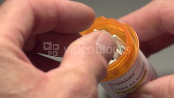 Man taking a marijuana joint out of a pill bottle